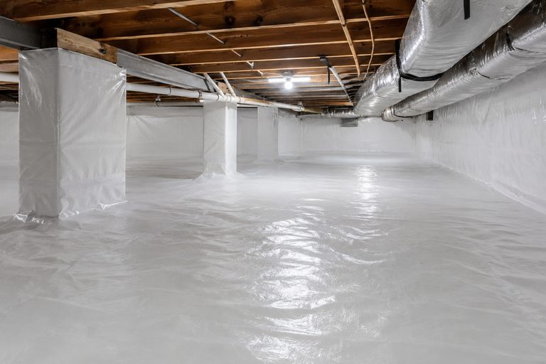 Bright, fully encapsulated crawl space with sealed white vapor barrier on floor, walls, and piers